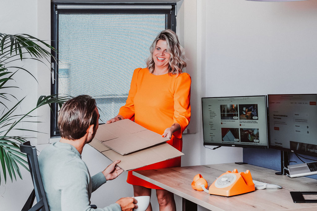 Twee collega's van Pack Company aan een bureau.